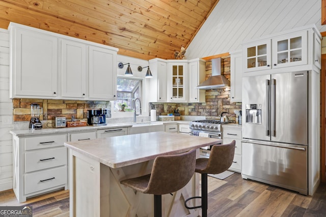 kitchen featuring premium appliances, white cabinetry, a kitchen island, and wall chimney exhaust hood