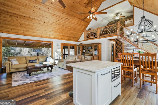 kitchen featuring stainless steel microwave, wood walls, hardwood / wood-style floors, decorative light fixtures, and white cabinets