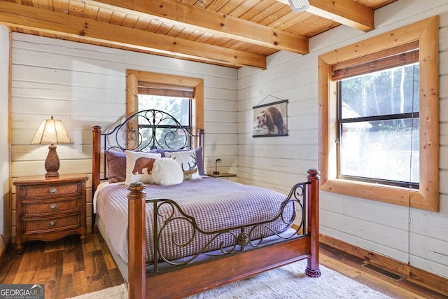 bedroom with beam ceiling, dark hardwood / wood-style flooring, wooden walls, and wood ceiling