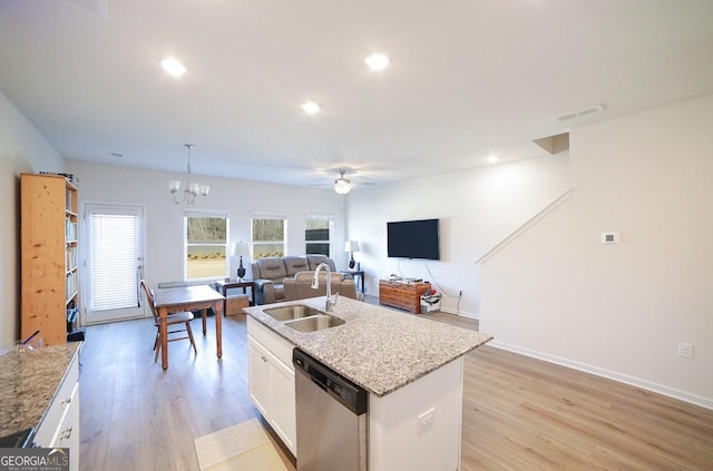 kitchen featuring pendant lighting, a kitchen island with sink, ceiling fan with notable chandelier, stainless steel dishwasher, and white cabinetry