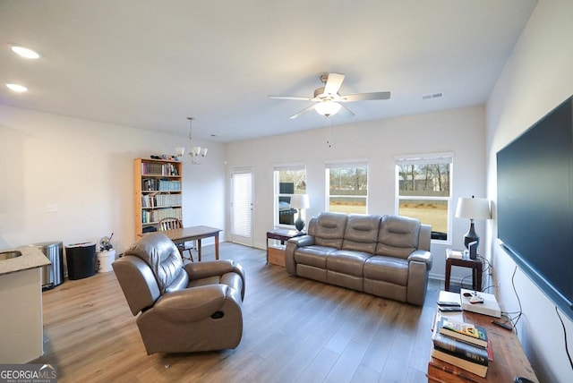 living room with ceiling fan with notable chandelier and wood-type flooring