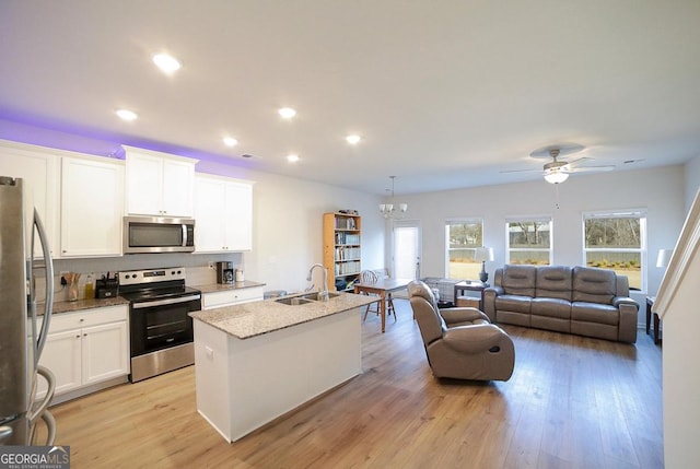 kitchen featuring white cabinets, appliances with stainless steel finishes, a center island with sink, and sink