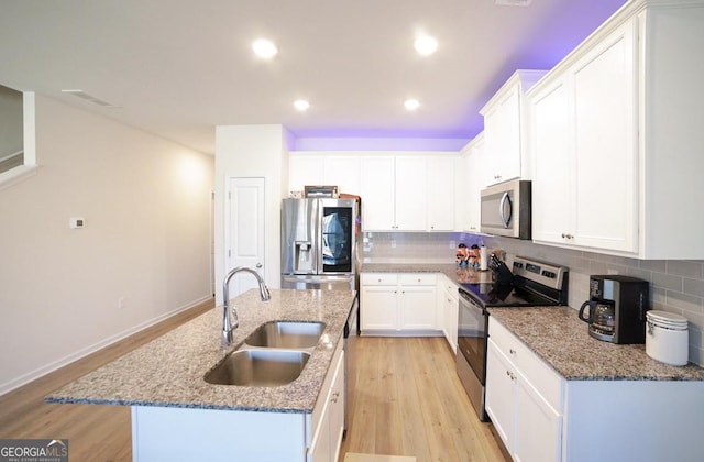 kitchen featuring white cabinetry, sink, stainless steel appliances, tasteful backsplash, and an island with sink