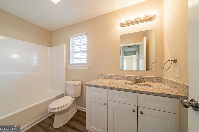 full bathroom with vanity, wood-type flooring, a textured ceiling, toilet, and shower / bathing tub combination