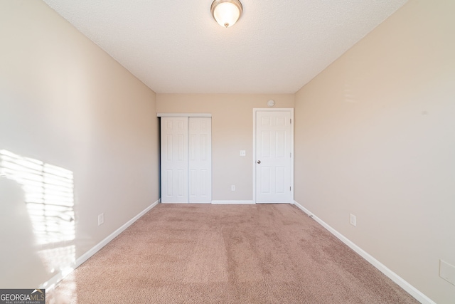 unfurnished bedroom with carpet, a textured ceiling, and a closet