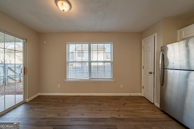 unfurnished dining area with a textured ceiling, plenty of natural light, and dark hardwood / wood-style floors