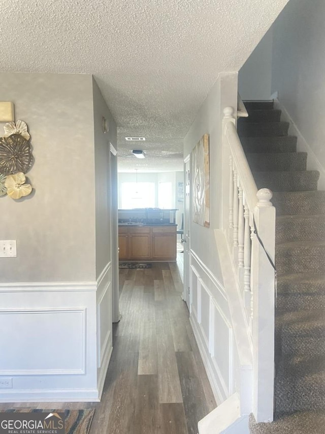 hallway with a textured ceiling and dark wood-type flooring