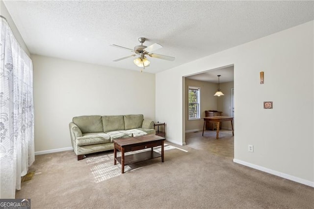 carpeted living room with ceiling fan and a textured ceiling