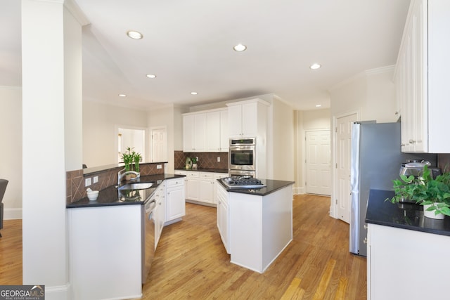 kitchen featuring backsplash, sink, light hardwood / wood-style floors, white cabinetry, and stainless steel appliances