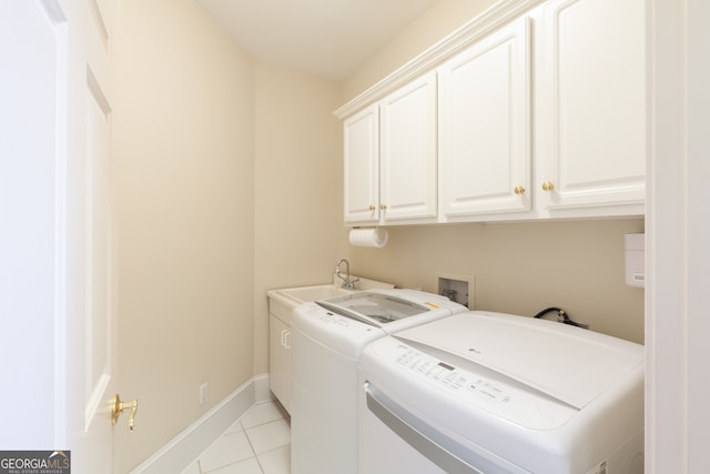 laundry area with cabinets, light tile patterned floors, washer and clothes dryer, and sink