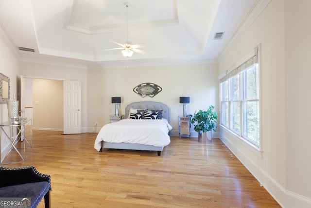 bedroom with a raised ceiling, ceiling fan, crown molding, and light hardwood / wood-style floors