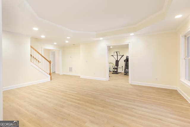 interior space with a tray ceiling, crown molding, and light wood-type flooring