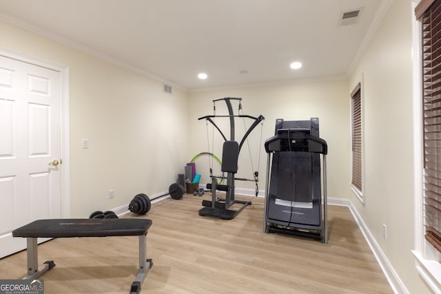 workout room with crown molding and light hardwood / wood-style flooring