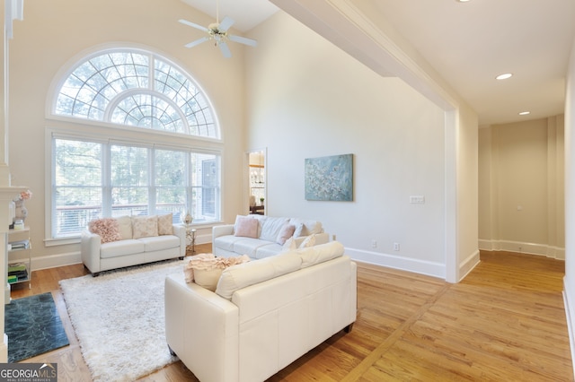 living room featuring ceiling fan, wood-type flooring, and a high ceiling