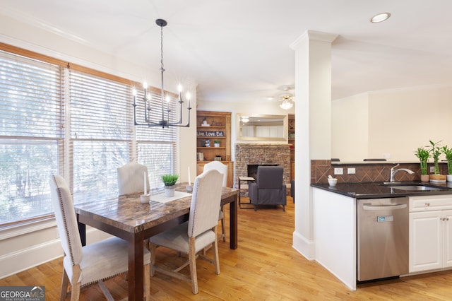 dining area featuring sink, light hardwood / wood-style floors, ceiling fan with notable chandelier, and ornamental molding