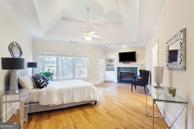 bedroom with hardwood / wood-style floors, a tray ceiling, and ceiling fan