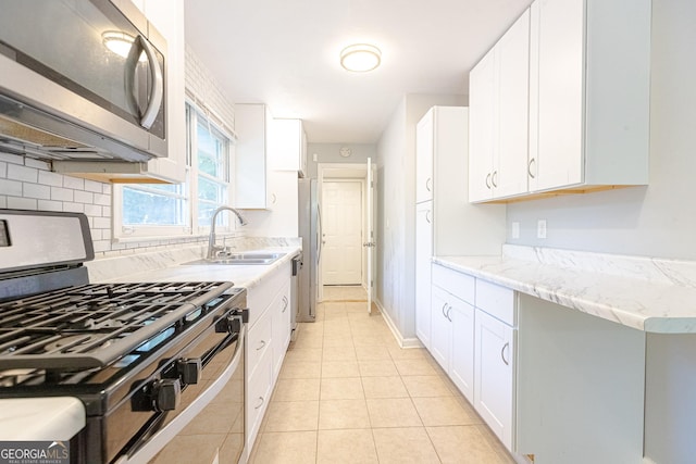 kitchen with white cabinets, light tile patterned floors, sink, and appliances with stainless steel finishes