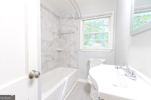 full bathroom featuring tiled shower / bath combo, toilet, and sink