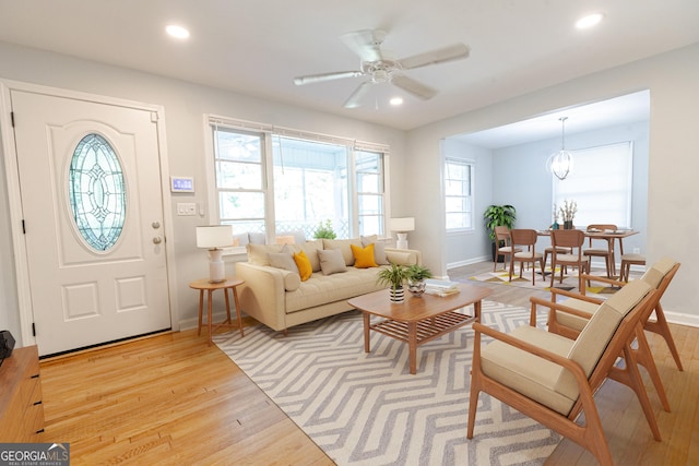 interior space featuring ceiling fan with notable chandelier and light wood-type flooring