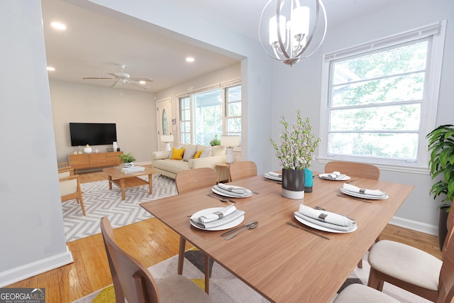 dining space featuring a wealth of natural light, light hardwood / wood-style floors, and ceiling fan with notable chandelier