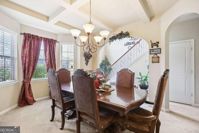 dining room with light carpet, a chandelier, beam ceiling, arched walkways, and baseboards