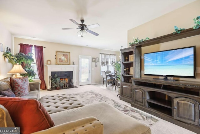 living area featuring a fireplace with flush hearth and ceiling fan