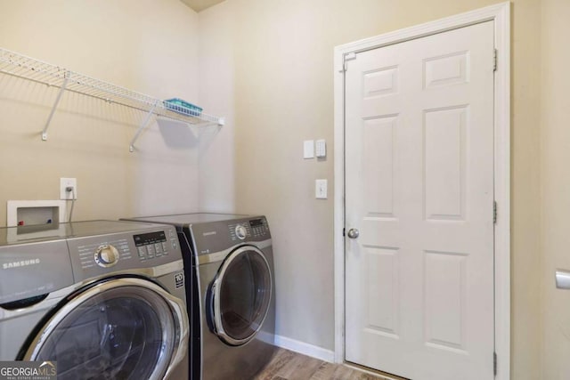 laundry area featuring washing machine and clothes dryer, baseboards, and wood finished floors