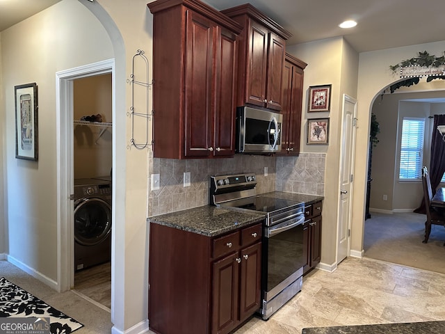 kitchen with appliances with stainless steel finishes, arched walkways, washer / clothes dryer, backsplash, and baseboards