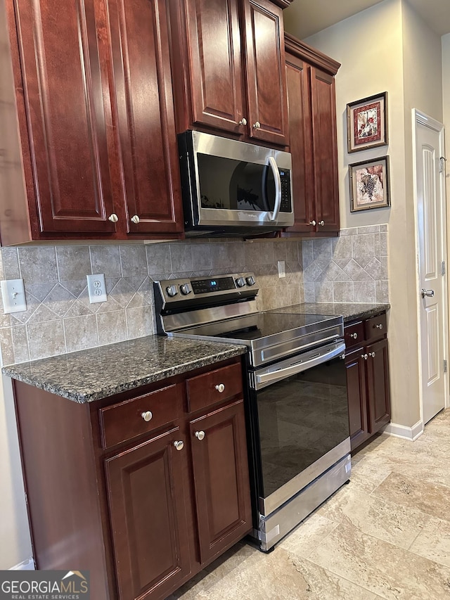 kitchen with stainless steel appliances, tasteful backsplash, baseboards, dark stone countertops, and reddish brown cabinets