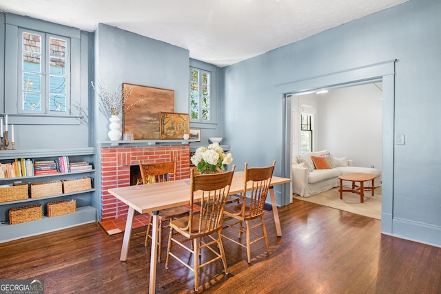 dining space featuring a brick fireplace and wood-type flooring