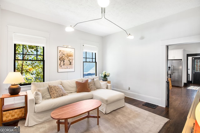 living room with a healthy amount of sunlight, a textured ceiling, and dark hardwood / wood-style floors