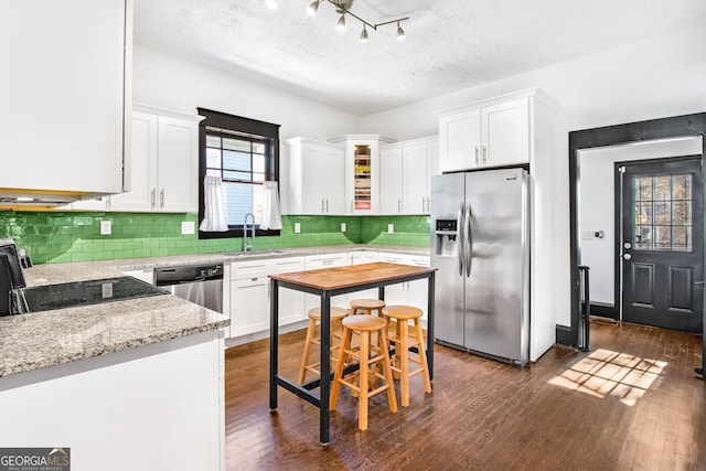 kitchen with sink, white cabinets, dark wood-type flooring, light stone counters, and stainless steel appliances