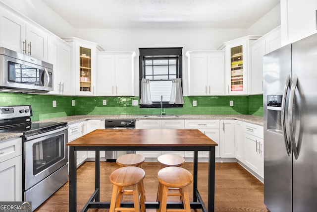 kitchen with light stone countertops, sink, white cabinetry, and appliances with stainless steel finishes