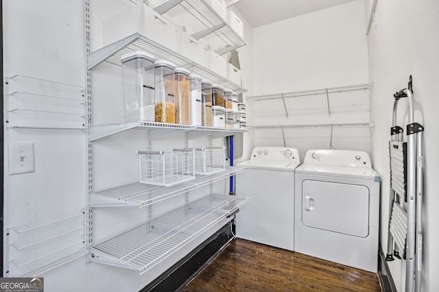 clothes washing area with washer and clothes dryer and dark wood-type flooring