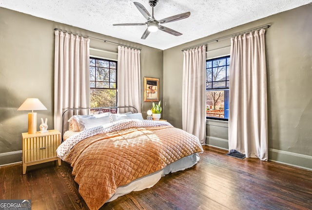 bedroom featuring ceiling fan, dark wood-type flooring, and a textured ceiling