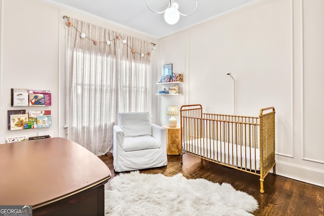 bedroom with crown molding, a crib, and hardwood / wood-style flooring