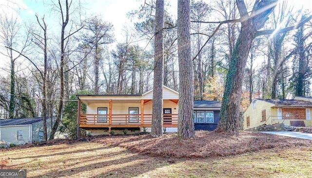 view of front of house featuring a porch, a front lawn, and a storage shed