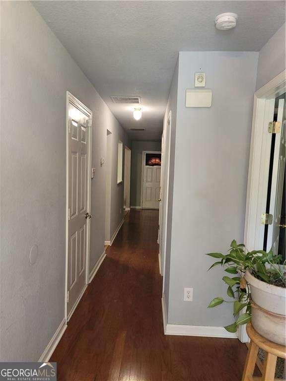 corridor featuring a textured ceiling and dark wood-type flooring