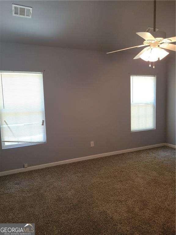 spare room featuring carpet, ceiling fan, and a healthy amount of sunlight