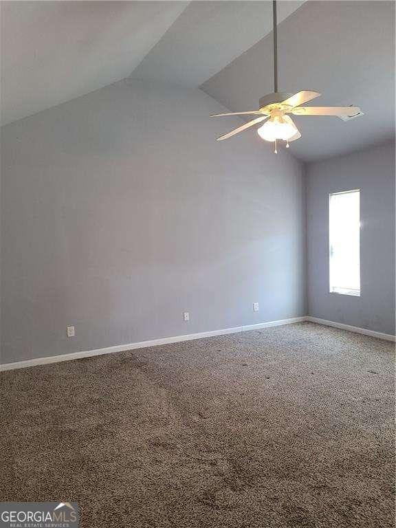 carpeted spare room with ceiling fan and lofted ceiling