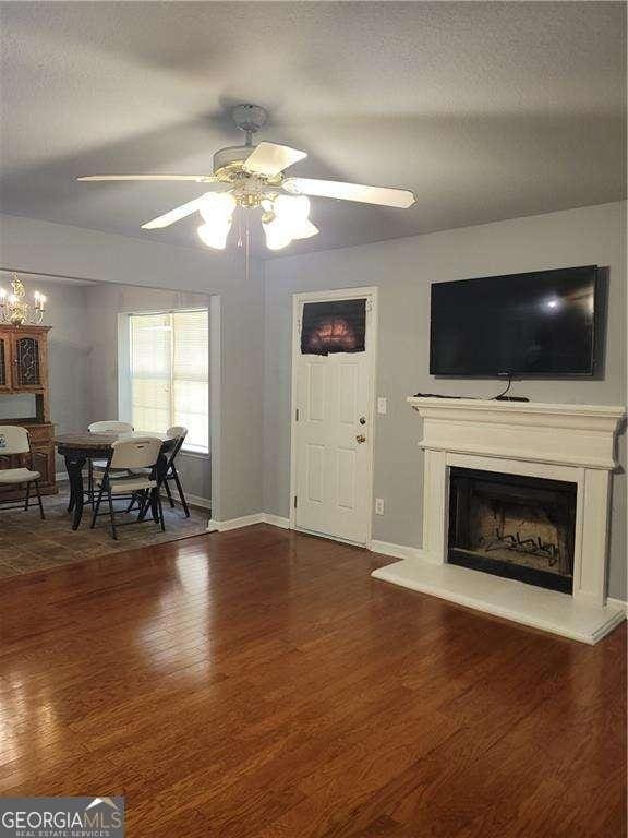 living room featuring ceiling fan, dark hardwood / wood-style floors, and a textured ceiling