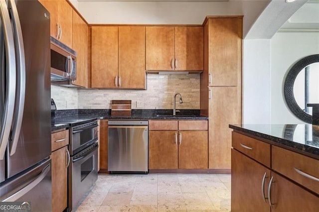 kitchen featuring dark stone countertops, sink, stainless steel appliances, and tasteful backsplash