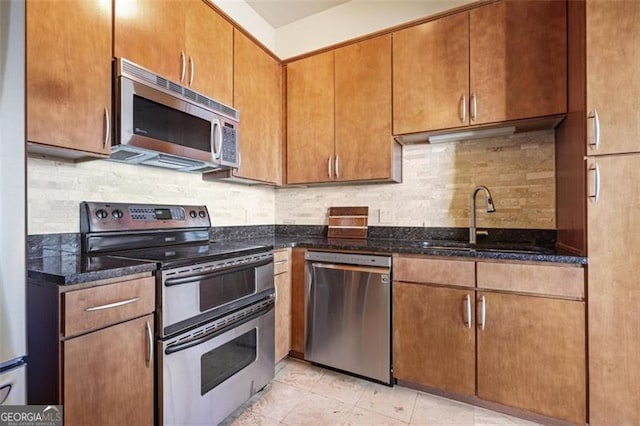 kitchen featuring dark stone countertops, sink, light tile patterned floors, and stainless steel appliances