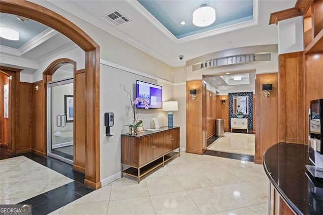 interior space featuring light tile patterned floors, crown molding, and a tray ceiling