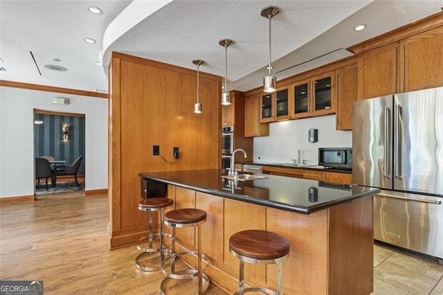 kitchen with a breakfast bar area, sink, stainless steel appliances, and decorative light fixtures