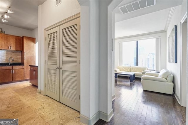 corridor featuring crown molding, sink, and light wood-type flooring