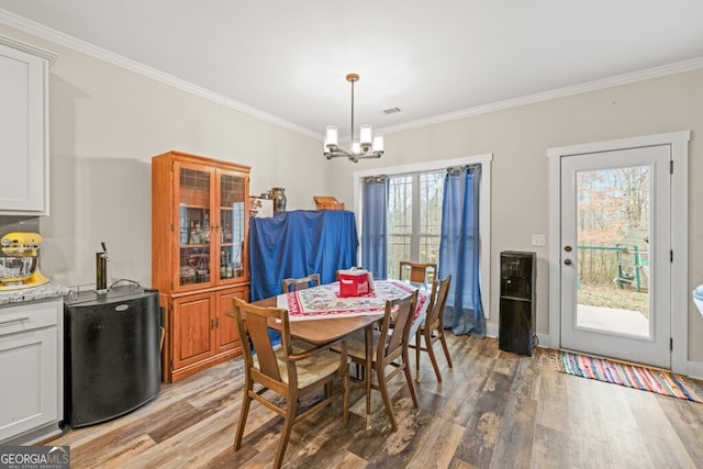 dining space with crown molding, hardwood / wood-style floors, and a notable chandelier