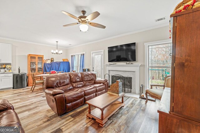 192 Celestial Run, Winder, GA 30680 - living room featuring a ceiling fan, light wood-type flooring, ornamental molding, a chandelier, and a fireplace with raised hearth