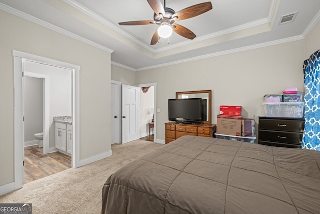 carpeted bedroom featuring a raised ceiling, ceiling fan, ensuite bathroom, and ornamental molding