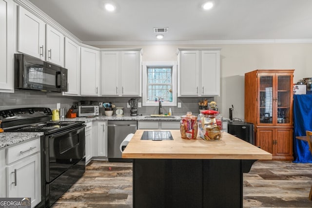 kitchen with dark wood-type flooring, black appliances, white cabinets, light stone countertops, and a kitchen island